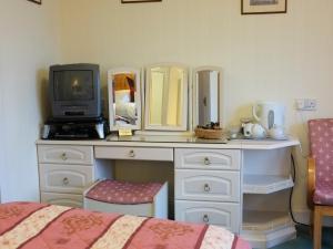 a bedroom with a dresser with a tv and a bed at The Well House in Pitlochry