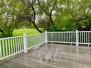 einen weißen Zaun auf einer Holzterrasse mit Bäumen in der Unterkunft The Prospect Point Penthouse- Yard & Parking, Minutes From Falls & Casino by Niagara Hospitality in Niagara Falls