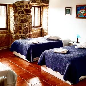 a bedroom with two beds and a stone wall at Casa Dom Yahya in Belmonte