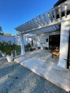 une pergola blanche sur une maison avec une terrasse dans l'établissement Aruba, à Jupiter