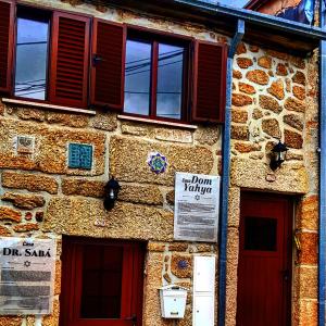 um edifício de pedra com portas e janelas vermelhas em Casa Dom Yahya em Belmonte