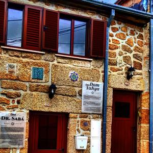 a stone building with red doors and windows at Casa Dom Yahya in Belmonte