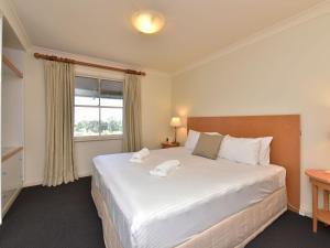 a bedroom with a large white bed with a window at Villa 2br Ferre Villa located within Cypress Lakes Resort in Pokolbin