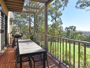 a deck with a wooden table and chairs on a porch at Villa 3br Tranquility located within Cypress Lakes Resort in Pokolbin