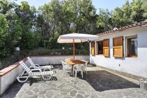 een patio met een tafel en stoelen en een parasol bij La casina in Capoliveri