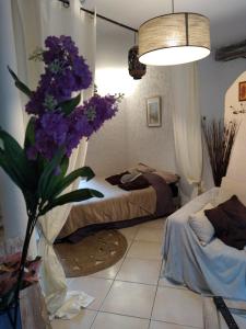 a bedroom with two beds and a vase of purple flowers at Le Gîte de la Tinée in Clans