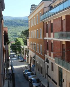 une rue de la ville avec des voitures garées sur le côté d'un bâtiment dans l'établissement Il Sogno di Hypnos, à LʼAquila
