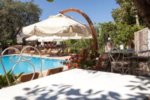 uma mesa com um guarda-sol ao lado de uma piscina em Green Peace Hotel em Oludeniz