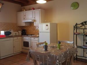 eine Küche mit einem Tisch mit Stühlen und einem weißen Kühlschrank in der Unterkunft Gîte Villemontais, 4 pièces, 6 personnes - FR-1-496-121 in Villemontais