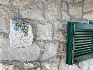 a stone wall with a sign with grapes on it at Apartments Vila Vino in Sveta Nedelja