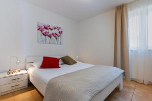 1 dormitorio con cama blanca y almohadas rojas en Apartments Dolac, en Nerezine