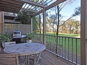 un patio con mesa y sillas en una terraza en Villa 3br Beaujolais Villa located within Cypress Lakes Resort, en Pokolbin