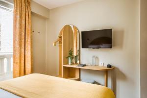 een slaapkamer met een bed, een bureau en een televisie bij Hôtel AMI - Orso Hotels in Parijs