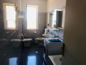 CASA LA SCOGLIERA DEI BRONZI في رياس مارينا: حمام به مغسلتين ومرحاض وحوض استحمام