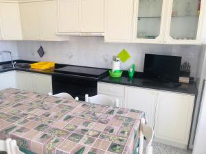 eine Küche mit einem Tisch und weißen Schränken in der Unterkunft CASA LA SCOGLIERA DEI BRONZI in Riace Marina