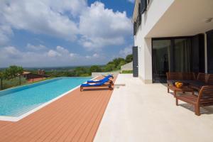 ヴィシュニャンにあるVilla Annaの家の隣に木製の椅子2脚が備わるスイミングプール