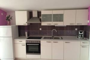 a white kitchen with white cabinets and a sink at just on the beach 'Zamalin' in Tribunj