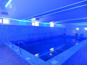 uma casa de banho com uma piscina com luzes azuis em Hotel Traian Caciulata em Călimăneşti