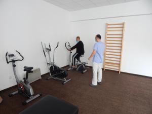 two people standing in a gym with exercise equipment at Hotel Traian Caciulata in Călimăneşti