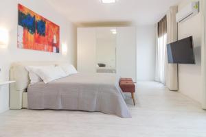 a white bedroom with a bed and a tv at Villa Mary in Olbia