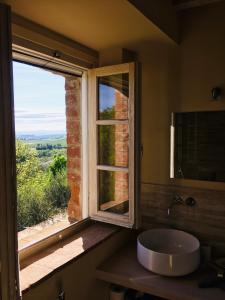 baño con lavabo y ventana con vistas. en La Falconara en Montepulciano