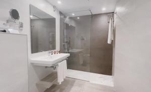 a white bathroom with a sink and a shower at Comitas Floramar in Cala Galdana