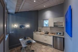 a kitchen with white cabinets and a table in it at Le Clos Des Bourges in Le Rouret