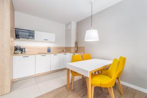 cocina y comedor con mesa blanca y sillas amarillas en Bel Mare Resort Apartment with Parking by Renters en Międzyzdroje