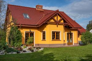 a yellow house with a red roof at Dom u podnóża Biskupiej Kopy in Jarnołtówek