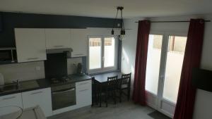 a kitchen with white cabinets and a table and chairs at Logements Le232 fr in Chasseneuil-du-Poitou