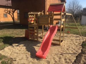 un parque infantil con un tobogán rojo en la arena en MINARDI vendégházak en Berekfürdő