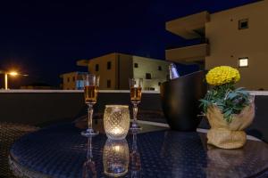 Hotel Vila White في تروغير: طاولة مع كأسين من النبيذ و مزهرية مع الزهور