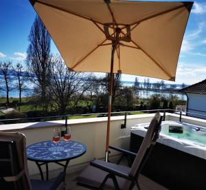 una mesa con dos copas de vino y una sombrilla en Uferloft, en Immenstaad am Bodensee