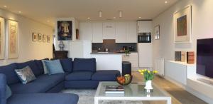 ein Wohnzimmer mit einem blauen Sofa und einer Küche in der Unterkunft Zeewaarts in Cadzand-Bad in Cadzand-Bad