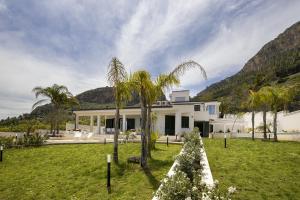 une maison blanche avec des palmiers dans la cour dans l'établissement Kafara Resort- Villas and Pool by Lisca Bianca Rental, à Santa Flavia