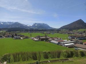 a village with a green field and mountains in the background at Haus Sonnenwinkl in Kössen