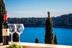 two wine glasses sitting on a table with a view of a lake at Villa Odak in Dubrovnik