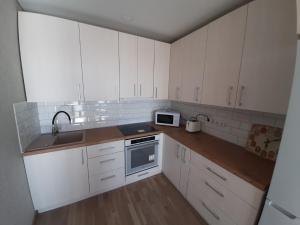 a kitchen with white cabinets and a sink and a microwave at Ramuma in Anykščiai