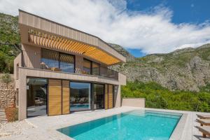 une maison avec une piscine à côté d'une montagne dans l'établissement Palazzo Vimbula - Five Star Luxury Villa, à Mokošica