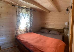 Cama en habitación de madera con ventana en Cabin House Dubovik en Cetinje