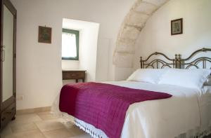 a bedroom with a large bed with a purple blanket at Trulli sul vignale in Masseria Santalachicca in Martina Franca