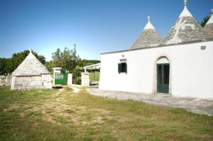 a white building with a green door and turrets at Trulli sul vignale in Masseria Santalachicca in Martina Franca