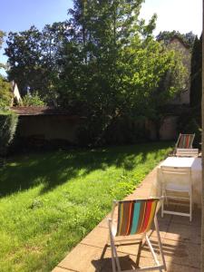 a lawn with a table and a chair in a yard at Maison Chevreuse, chambre chez l'habitant in Magny-les-Hameaux