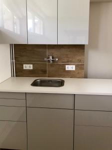 a kitchen with a sink and white cabinets at K House 5* Apartments in Kaufungen