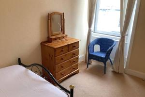 a bedroom with a dresser with a mirror and a chair at Ferry View in Largs