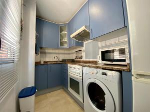 a kitchen with blue cabinets and a washer and dryer at Apartamento beach house in Las Palmas de Gran Canaria