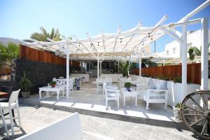 a patio with white tables and chairs under a pergola at Seaside Breeze in Kamari