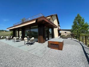 a house with chairs and tables on a gravel patio at Il GrecAle - Camere e Appartamenti in La Morra