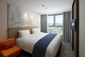 Holiday Inn Express Seoul Hongdae, an IHG Hotel في سول: غرفة فندقية بسرير كبير وكرسي