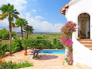 una casa con flores frente a una piscina en VILLA ALCAZAR, en Benitachell